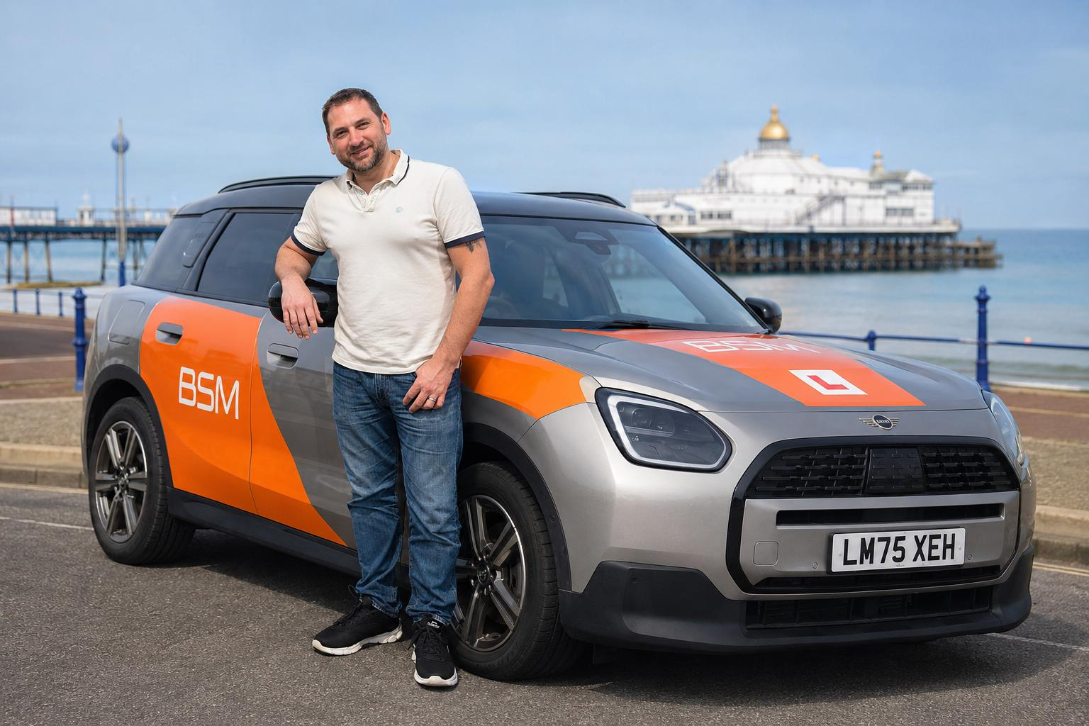 Friendly Eastbourne automatic driving instructor next to a modern silver car on the seafront